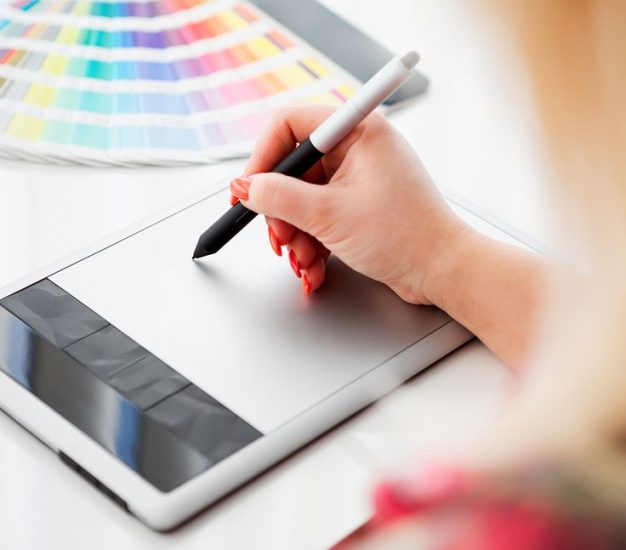 Graphic designer working on a digital tablet in the background with pantone palette